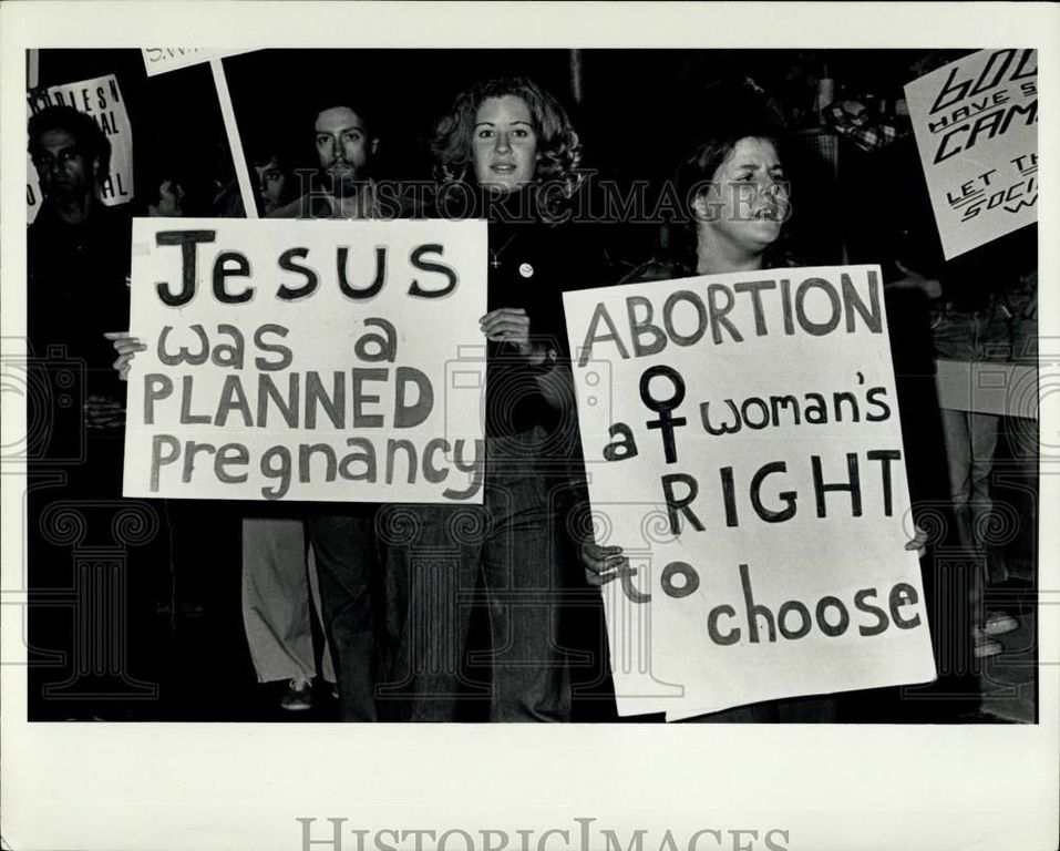 A black and white photo of two female protesters with signs saying: Jesus was a planned pregnancy and Abortion a womens right to choose