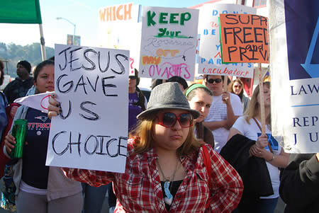 A photo of an abortion protest with a female holding a sign that says: Jesus Gave Us Choice