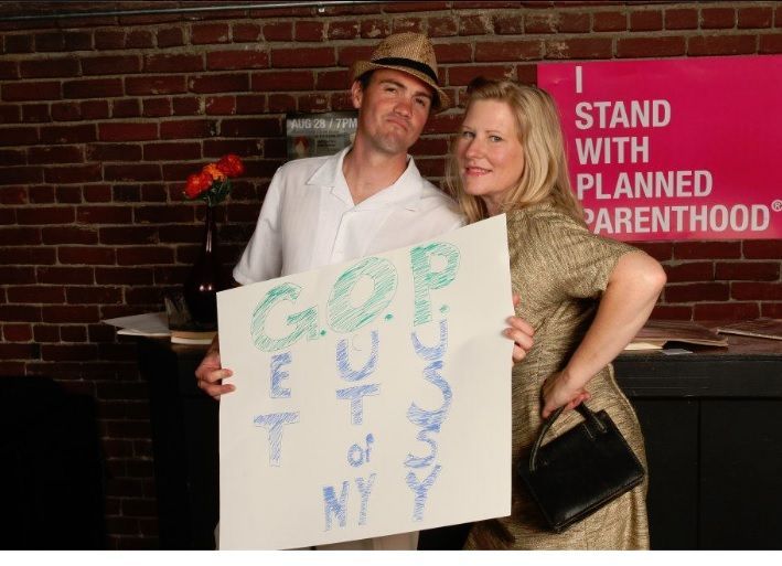 A photo of a man and women holding a sign at a Planned Parenthood party that says: GOP=Get Out of NY P***y