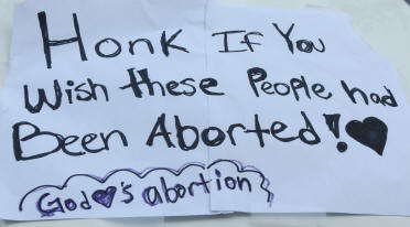A photo of a homemade poster that says: Honk If You Wish these People had Been Aborted! God Loves Abortion