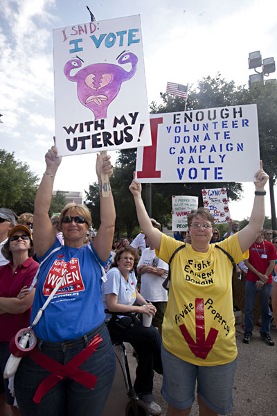 Two females at an abortion rally hold signs that say: I said-I vote with my uterus!