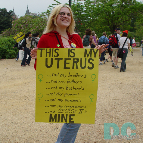 A female at a protest with the female sign drawn around her eye and she's holding a sign that says: This is my Uterus...not my brothers, not my fathers, not my husbands, not my governors, not my senators, not my congressman, not George II's MINE