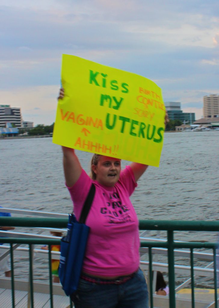 A single female protester holding a sign that says: Kiss my Uterus