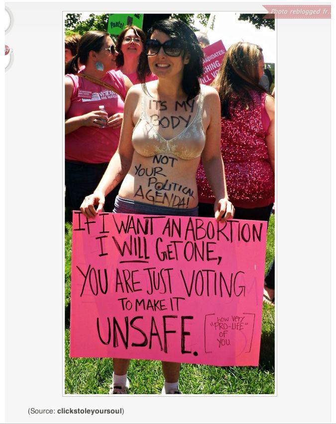 Photo of a female protestor in her bra with body paint that says Its my body not your politaical agenda! and a sign that says: If I want an abortion I will get one, You are jsut voting to make it unsafe. [How very pro-life of you]