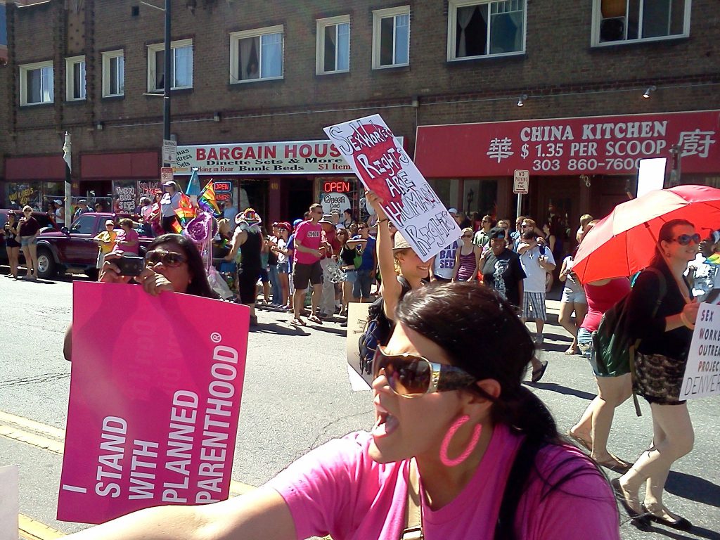 A photo from Pro-Choice Colorado's group marching in the Gay PRIDE parade. One lady is holding a sign that says "Sex workers rights are human rights"