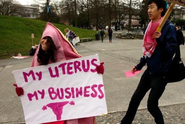 A photo of a female in a vagina costume with a sign saying: My Uterus My Business