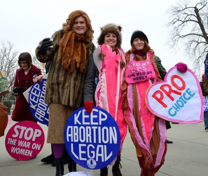 A photo of three pro-choice supporters with vagina costumes saying Read My Lips End War One Women