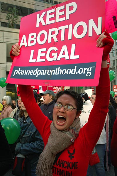 A photo of a lady shouting holding a sign that says "Keep Abortion Legal plannedparenthood.org"