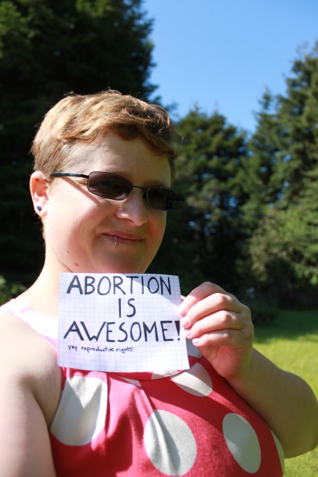 A photo of a women holding a sign that says: Abortion is Awesome! yay reproductive rights!