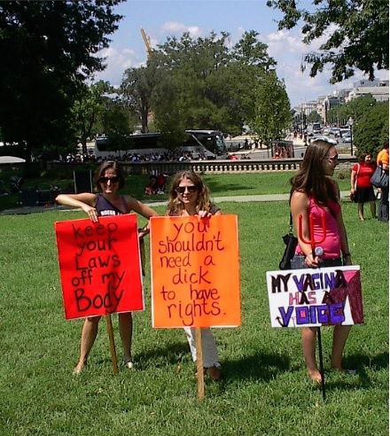 A picture of three women holding protest signs that say: Keep your laws off my body, You shouldnt need a d**k to have rights, My Vagina has a voice