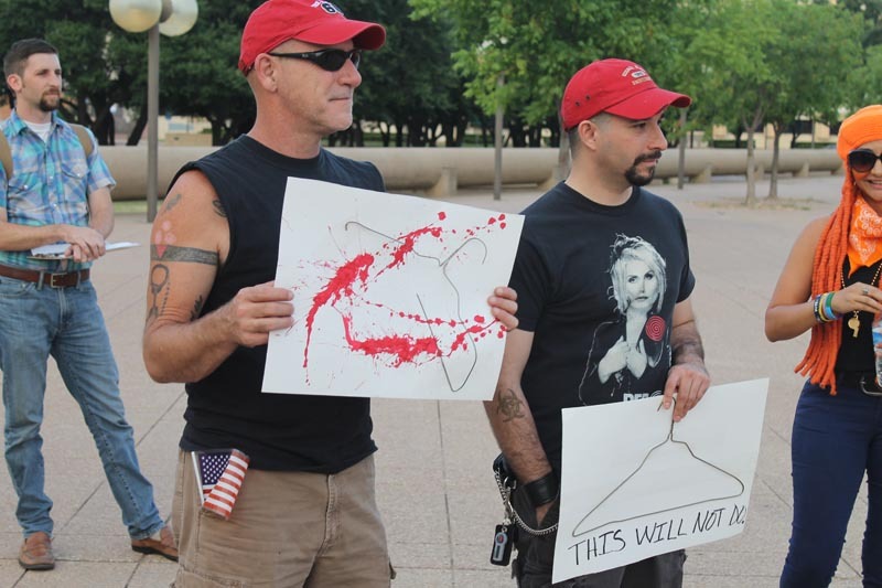 A photo of men holding posters with bloody coat hangers drawn on them