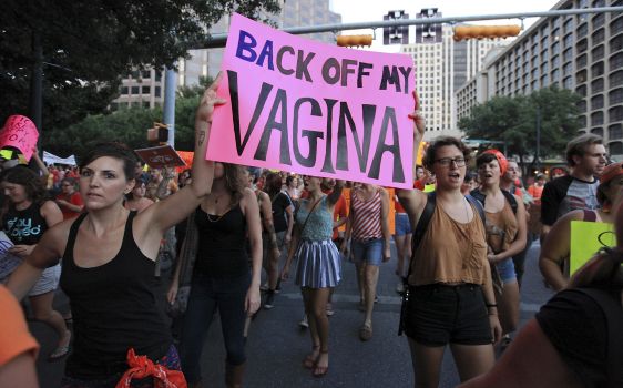 A photo of a march where two females are holding a sign reading: Back Off My Vagina