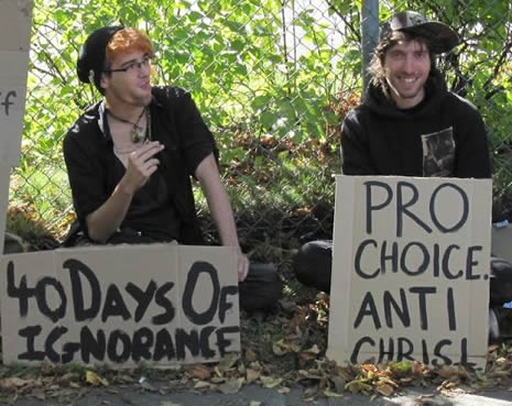 Two Males with cardboard signs that read: 40 Days Of Ignorance and Pro-Choice Anti-Christ