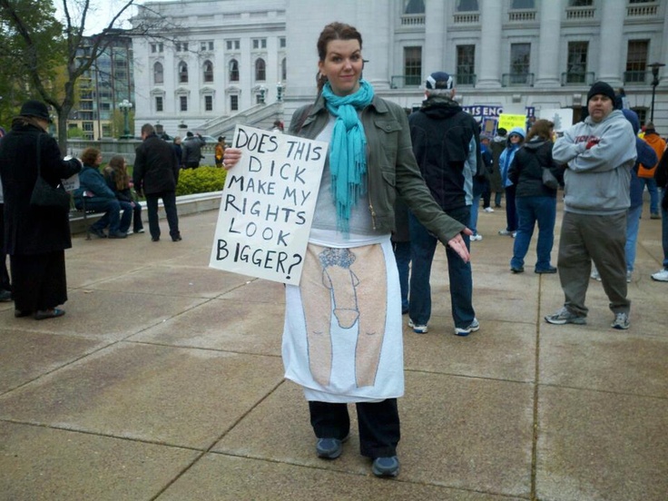 Photo of a female protestor with a drawing of a penis between her legs holding a sign saying: Does this dick make my rights look bigger?
