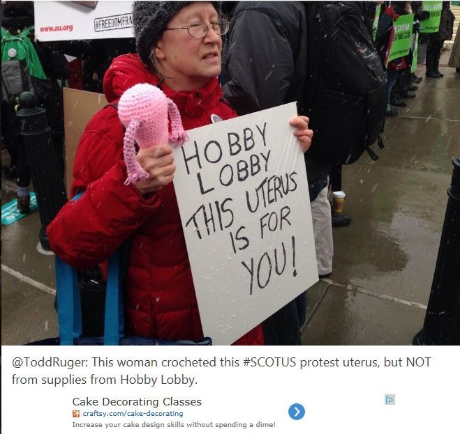 A grandmother holding a knitted uterus with a sign that says: Hobby Lobby This Uterus Is For You!
