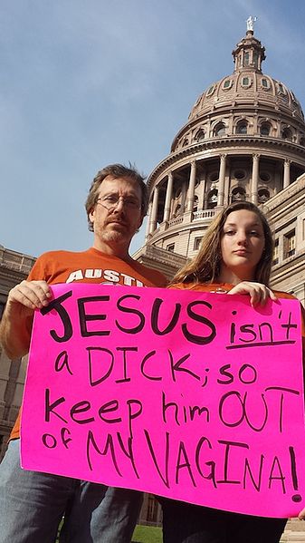 A photo of a Father and Daughter at the protests down in Austin TX with a sign that says: Jesus isn't a dick; So keep him out of my vagina!