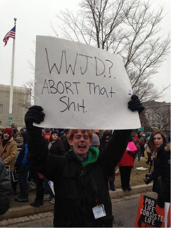 A male protester with a sign that says: WWJD? Abort that S**T
