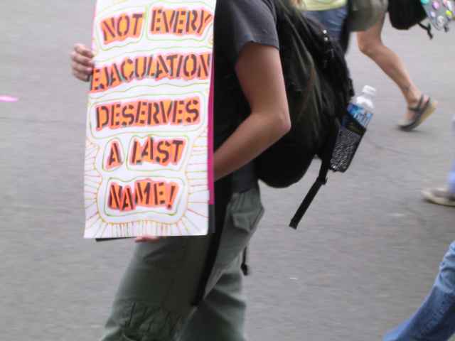 A male abortion supporter holding a sign that says: "Not every ejaculation deserves a last name!"