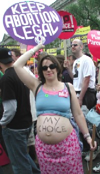 A pregnany mother has her belly expossed with the words My Choice across it. She is also holding a sign abover her head that says: "Keep Abortion Legal NOW"