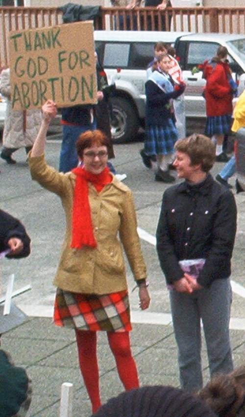 A photo of a female abortion supporter with a sign that says: "Thank God For Abortion"