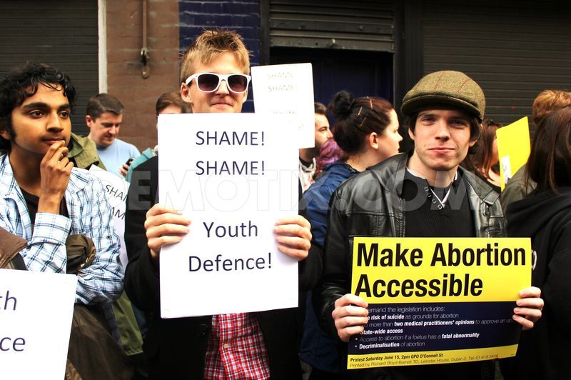 A photo of some young boys protesting for abortion rights with signs that say: Make Abortion Accessible, and Shame! Shame! Youth Defence!