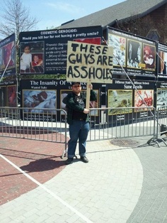 A Male Pro-choice protester with a sign that says: These guys are A**Holes referring to the Graphic photo display of aborted babies