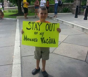 A picture of a young boy holding a bright sign that reads: STAY OUT of my Mommy's Vagina