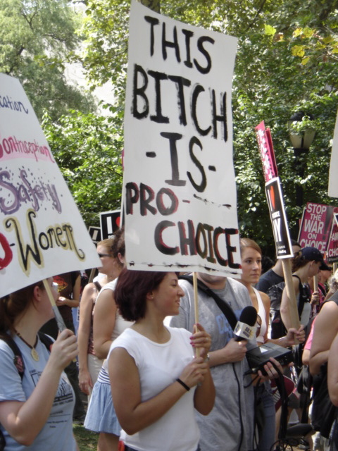A photo of a group of people protesting and a women is holding a sign that says: This B***H is Pro-Choice