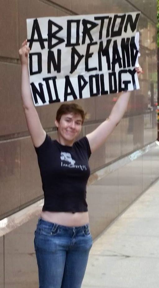 A photo of a female holding up a sign that reads: Abortion On Demand No Apology