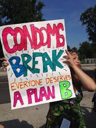 A photo of a femal abortion supporter holding a sign that says: Condoms Break Everyone Deserves A Plan B