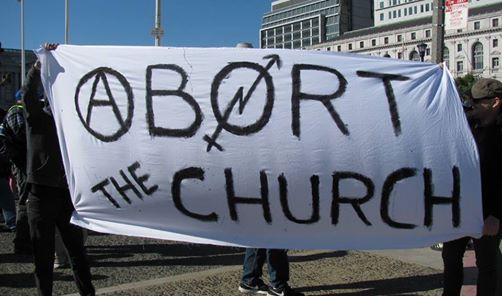 An abortion march with males holding a banner that reads: Abort the Church