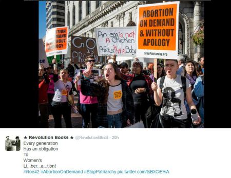 A picture taken at the Walk for Life from a pro-abortion group called Stop Patriarchy. They are holding posters that read: Abortion on Demand and Without Apology, An egg is not a chicken, A fetus is not a baby.