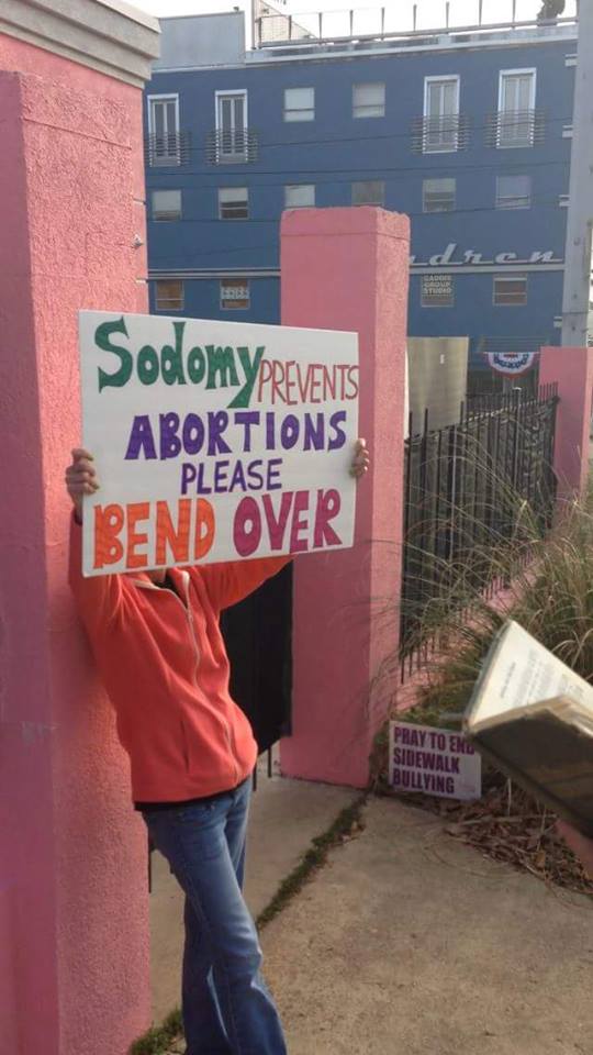 A picture of an abortion supporter holding a protest sign that says: "Sodomy Prevents Abortions Please Bend Over"