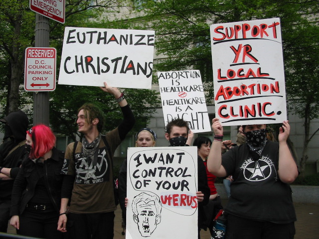 Pro-choice signs which read (from left to right) "Euthanize Christians", (Abortion is healthcare, healthcare is a right", "I want control of your uterus (featuring a sketch of what looks to be George W Bush)" and "Support yr local abortion clinic"