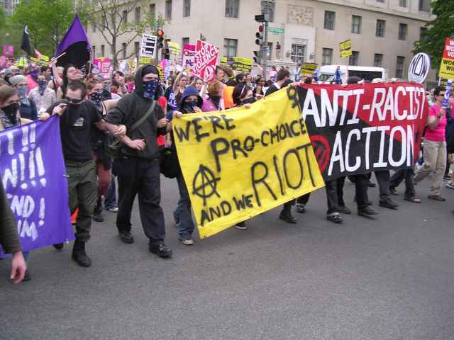 Pro-choice march features banners which read "We're pro-choice and we RIOT. (with anarchy symbol)" and "anti-racist action."