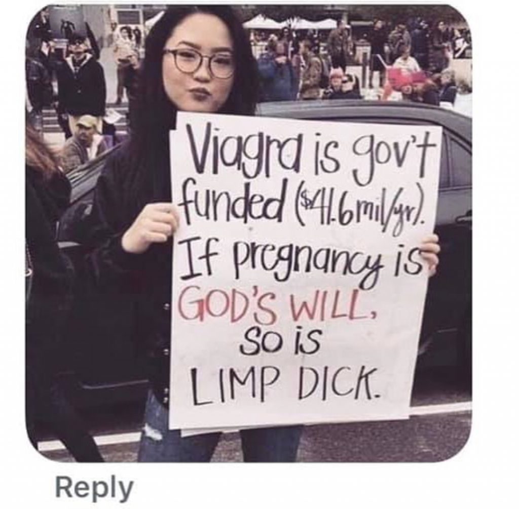 Woman holds a sign saying "Viagra is gov't funded ($41.6 mil/yr). If pregnancy is God's will, so is limp dick."