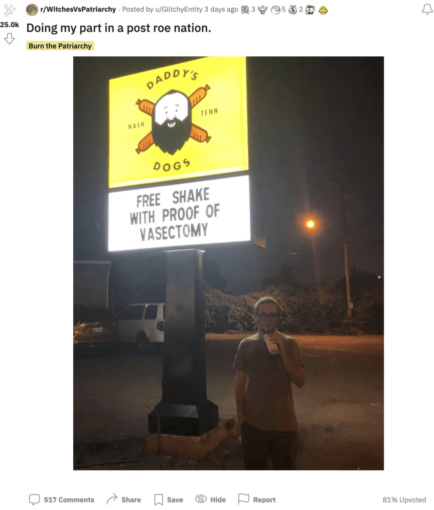 Man standing in front of a lit restaurant sign for "Daddy's Dogs" at night drinking a shake. On the sign behind him it reads, "Free shake with proof of vasectomy." This image was posted to a Reddit page with the caption, "Doing my part in a post roe nation." 